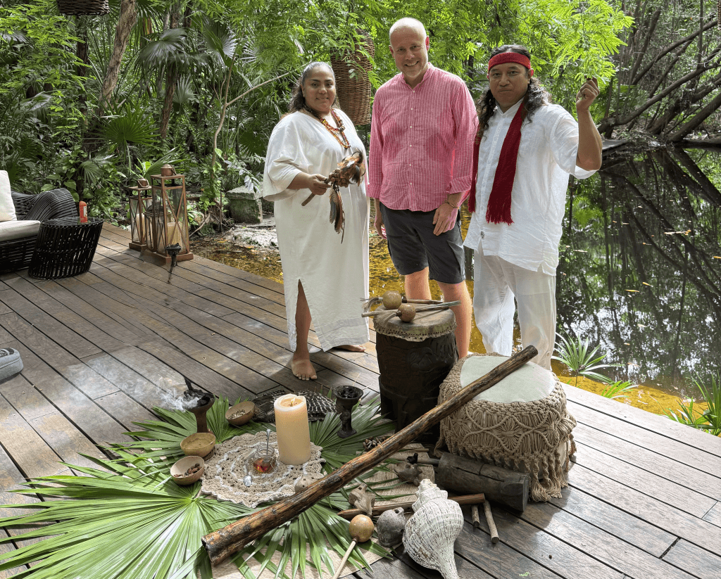 Laurent Delporte entouré de deux guérisseurs mayas en tenue blanche, devant un autel de cérémonie au bord du cénote