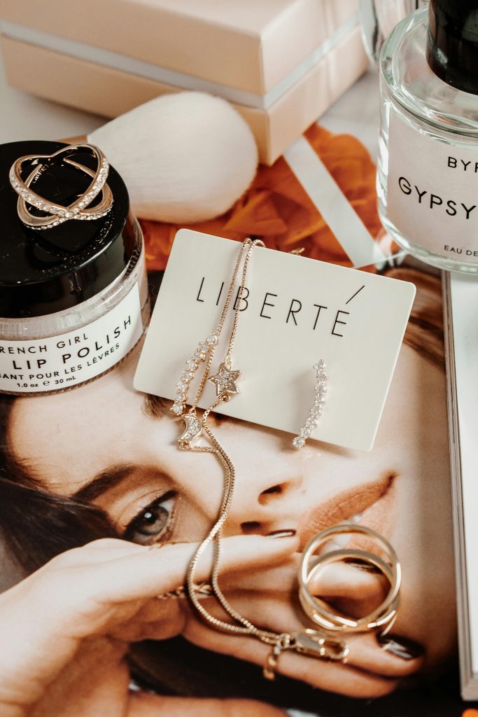 Close-up of jewelry, cosmetics, and fashion accessories arranged on a magazine with a luxury theme.