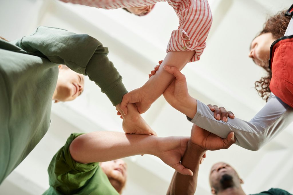 pexels-photo-6995379-6995379 A diverse group of people join hands forming a unity circle, symbolizing teamwork and cooperation.